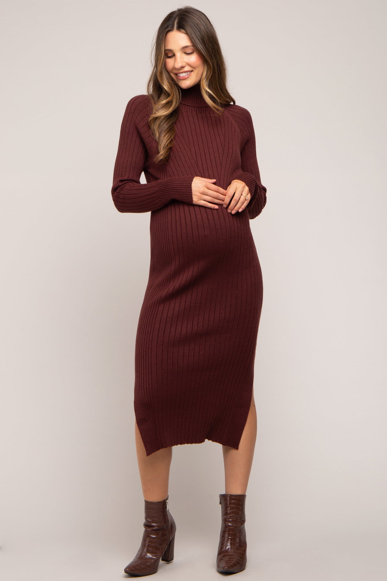 woman wearing a burgundy ribbed maternity dress with long sleeves and a side slit, showing her baby bump