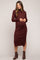 woman wearing a burgundy ribbed maternity dress with long sleeves and a side slit, showing her baby bump