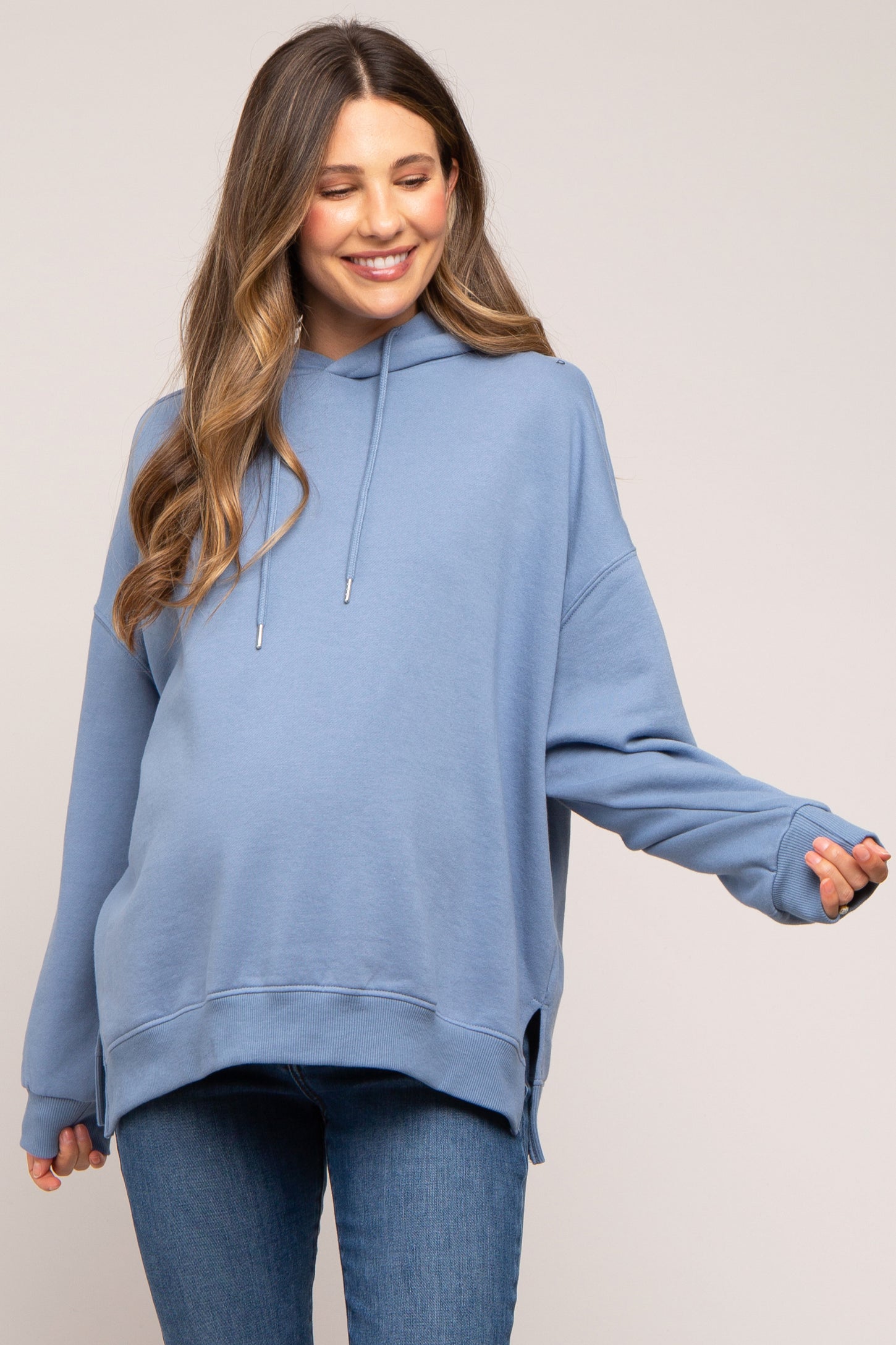 woman wearing a light blue oversized maternity hoodie with side slits and a visible baby bump