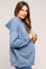 woman wearing a light blue maternity hoodie with a relaxed fit and drawstring hood, showing her baby bump