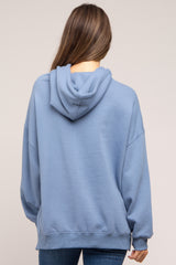 woman wearing a light blue oversized maternity hoodie with a hood, viewed from the back