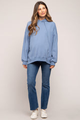 woman wearing a light blue oversized hoodie and skinny jeans, showing her baby bump