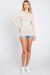 woman wearing a beige long sleeve top with a scoop neckline and styled with denim shorts and white sneakers