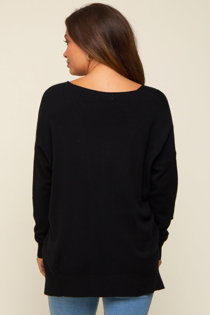 woman wearing a black oversized maternity sweater viewed from the back, with long sleeves and a loose fit