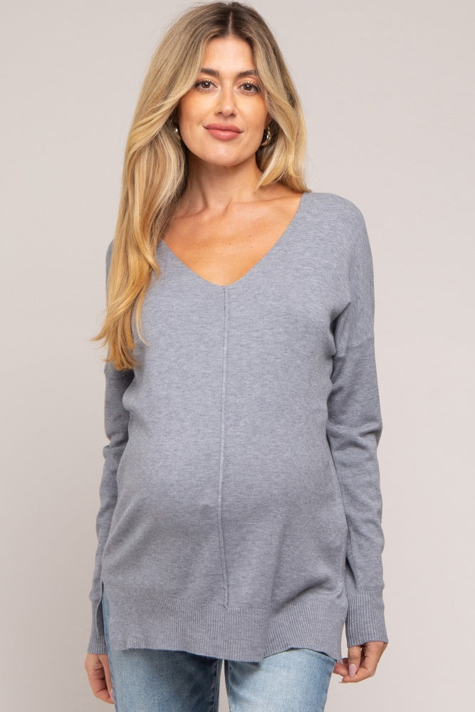 woman wearing a gray v-neck maternity sweater with a visible baby bump