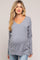 woman wearing a gray v-neck maternity sweater with a visible baby bump