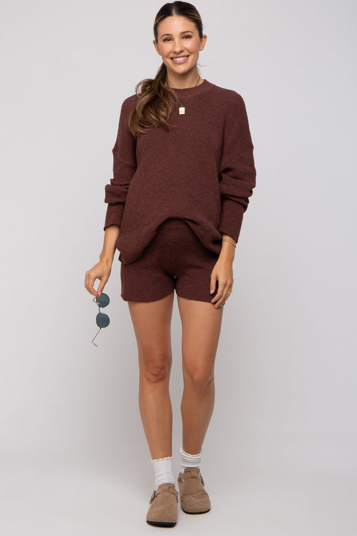 woman wearing a maroon maternity sweater and matching shorts, showcasing her baby bump, styled with sunglasses and light shoes