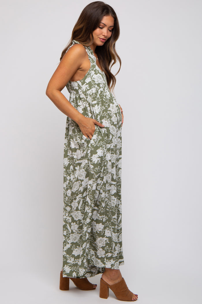 woman wearing a green floral maternity maxi dress with pockets and showing her baby bump