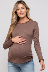 woman wearing a brown ribbed maternity top with ruffle details and holding her baby bump