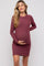 woman wearing a maroon long sleeve maternity dress with textured pattern and holding her baby bump