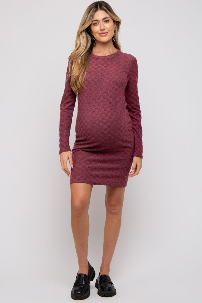woman wearing a burgundy long sleeve maternity dress with a textured pattern and visible baby bump