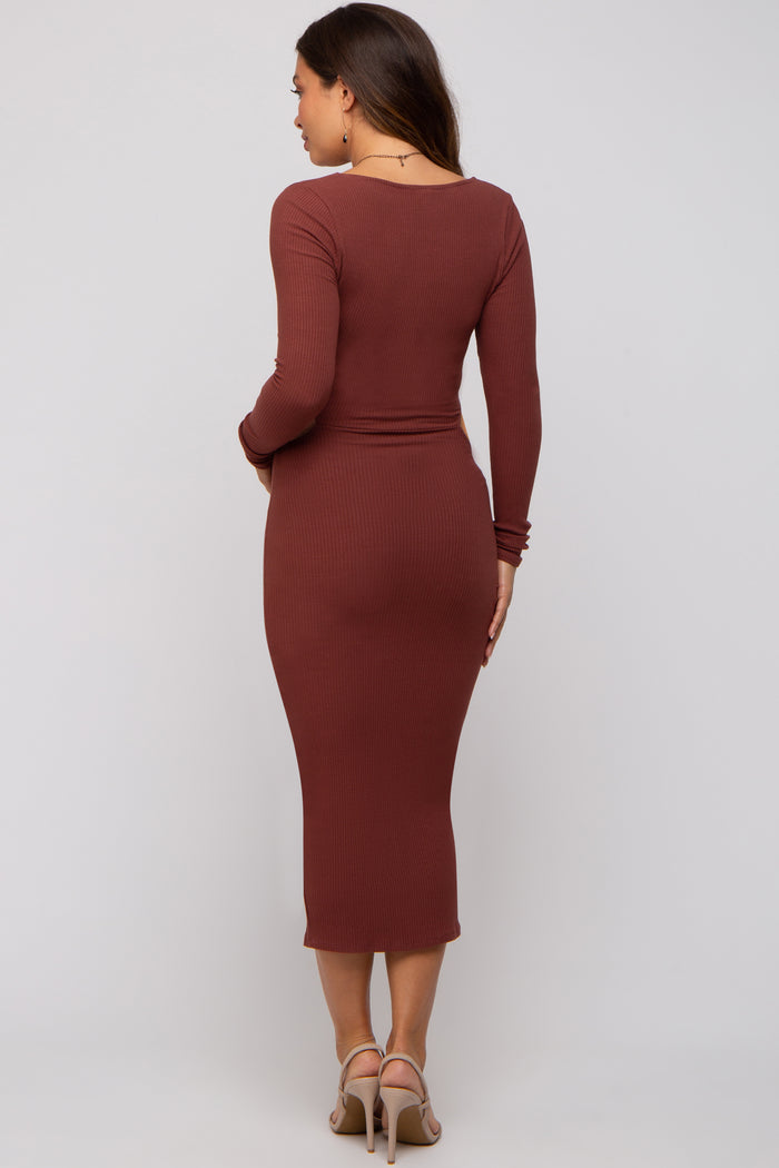woman wearing a rust brown ribbed maternity dress with long sleeves and a form-fitting silhouette, showing her baby bump
