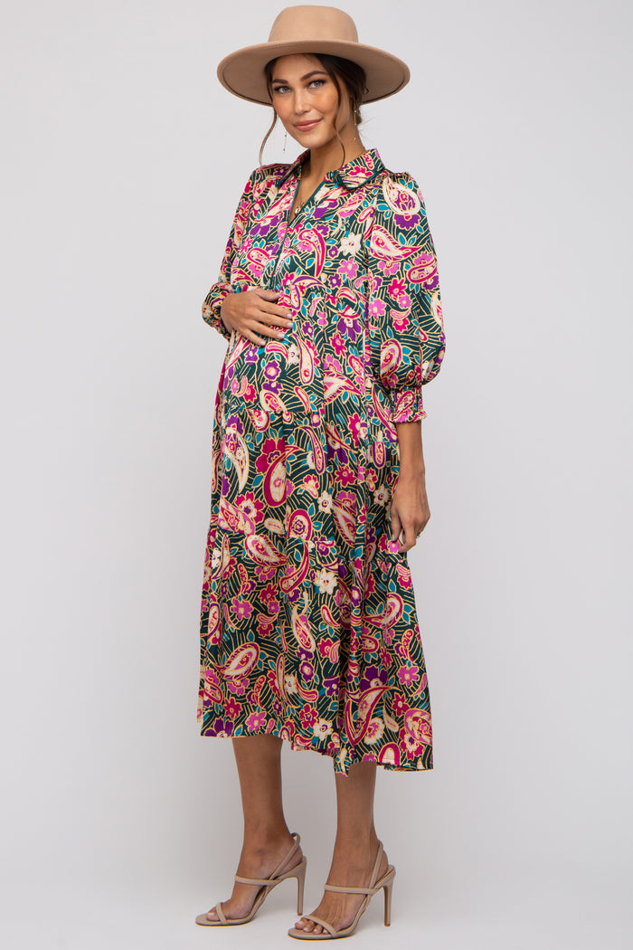 woman wearing a floral patterned maternity dress with puff sleeves and a baby bump, accessorized with a hat