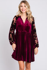 woman wearing a burgundy velvet dress with floral long sleeves and a v-neckline