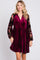 woman wearing a burgundy velvet dress with floral long sleeves and a v-neckline