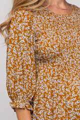 close-up of a woman wearing a smocked mustard floral maternity top with three-quarter sleeves