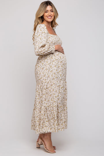 woman wearing a floral long sleeve maternity dress with a tiered skirt and holding her baby bump