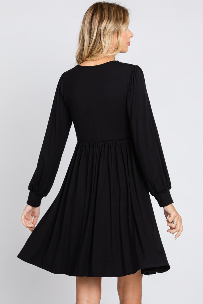woman wearing a black long sleeve dress with a fitted bodice and flared skirt, viewed from the back