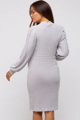 woman wearing a light gray maternity dress with long puff sleeves and a fitted silhouette, showcasing a baby bump from the back