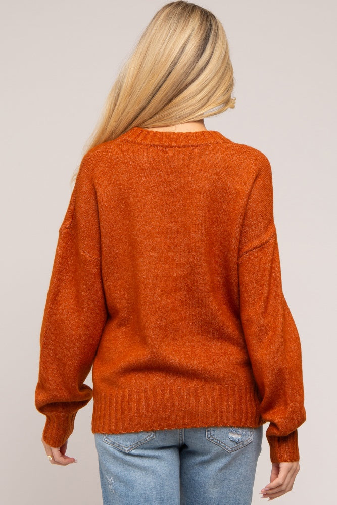 woman wearing an orange maternity sweater with a loose fit and long sleeves, viewed from the back