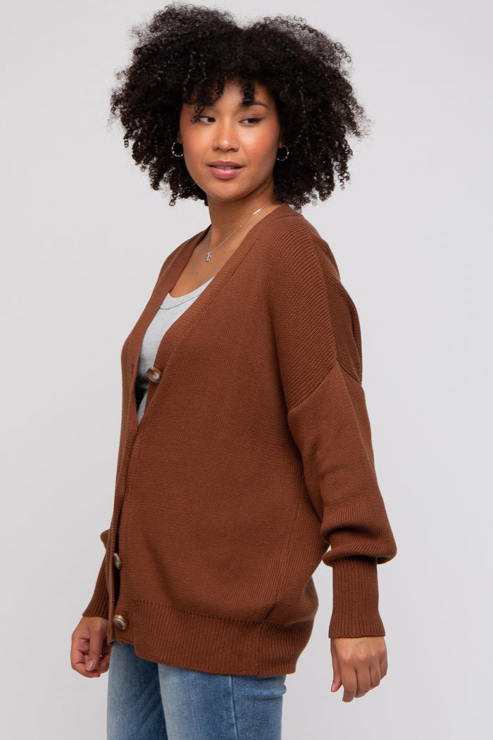 woman wearing a brown oversized cardigan with buttons, paired with a gray top and blue jeans