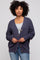 woman wearing a navy blue oversized cardigan with button details and a gray top underneath, standing against a light background