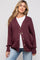 woman wearing a maroon maternity cardigan over a white top and light blue jeans