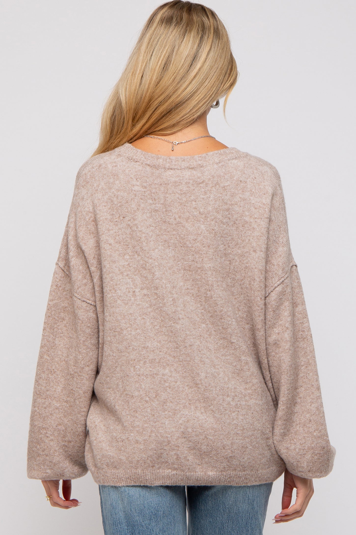 woman wearing a light brown oversized maternity sweater with a relaxed fit and drop shoulder sleeves