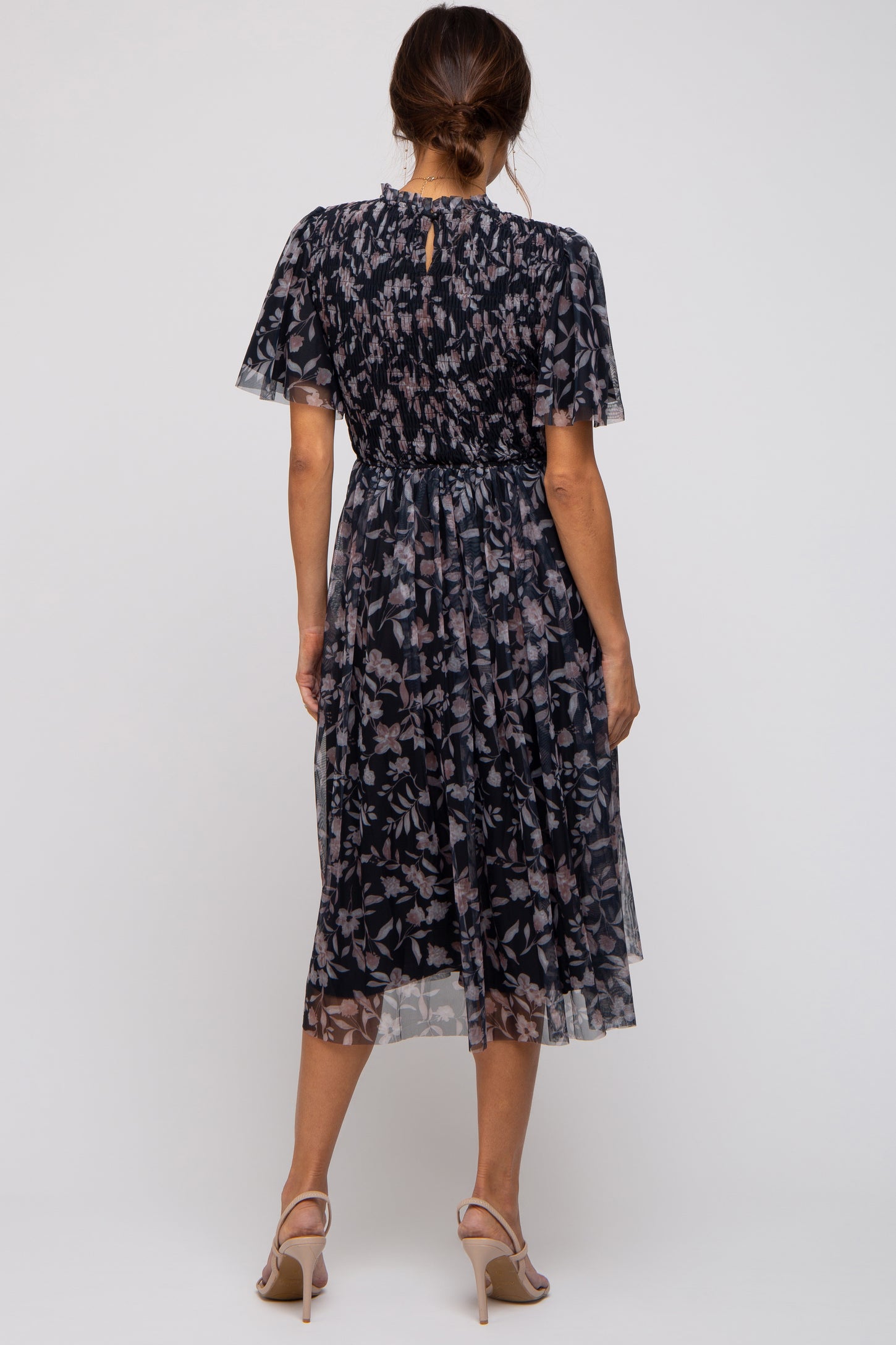 woman wearing a navy floral maternity dress with short flutter sleeves and a smocked waist, view from the back