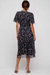 woman wearing a navy floral maternity dress with short flutter sleeves and a smocked waist, view from the back