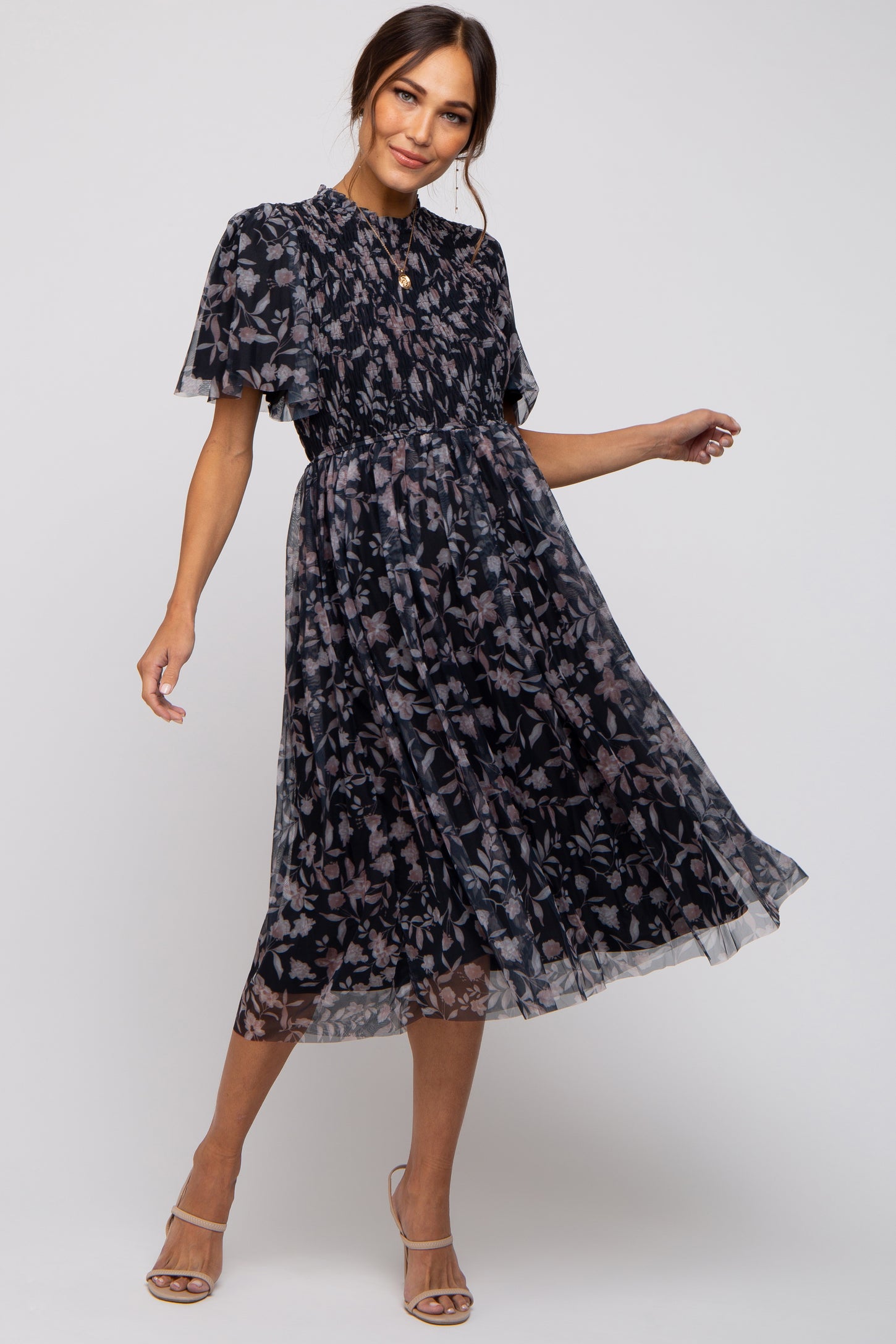 woman wearing a maternity floral print midi dress with short puff sleeves and a fitted waist, posing gracefully