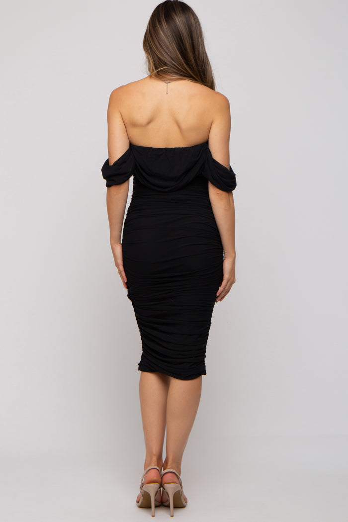 woman wearing a black off-the-shoulder maternity dress with ruched detail, showing a fitted silhouette from the back