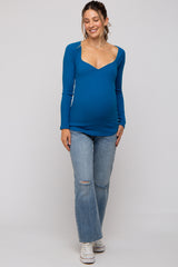 woman wearing a blue long sleeve maternity top with a sweetheart neckline and a baby bump, paired with distressed light jeans