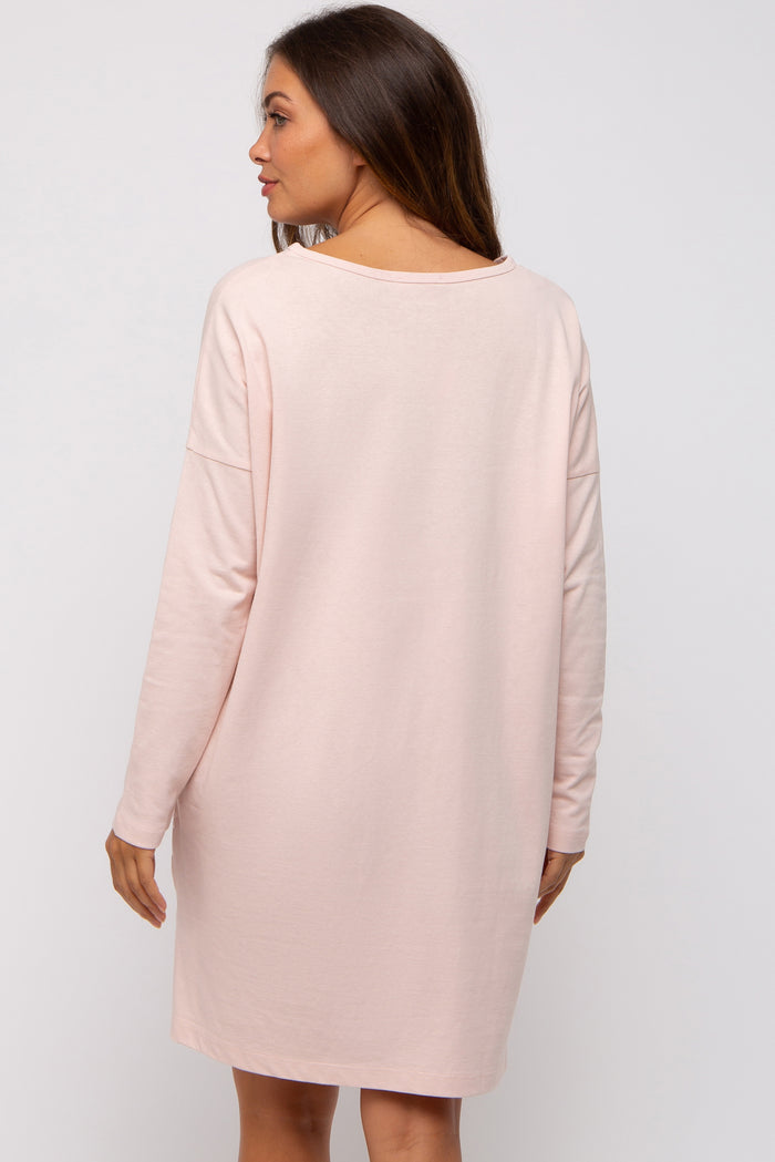 woman wearing a soft pink maternity dress with long sleeves, showing a relaxed fit and back view