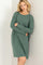 woman wearing a green long sleeve oversized t-shirt dress, posing against a wall