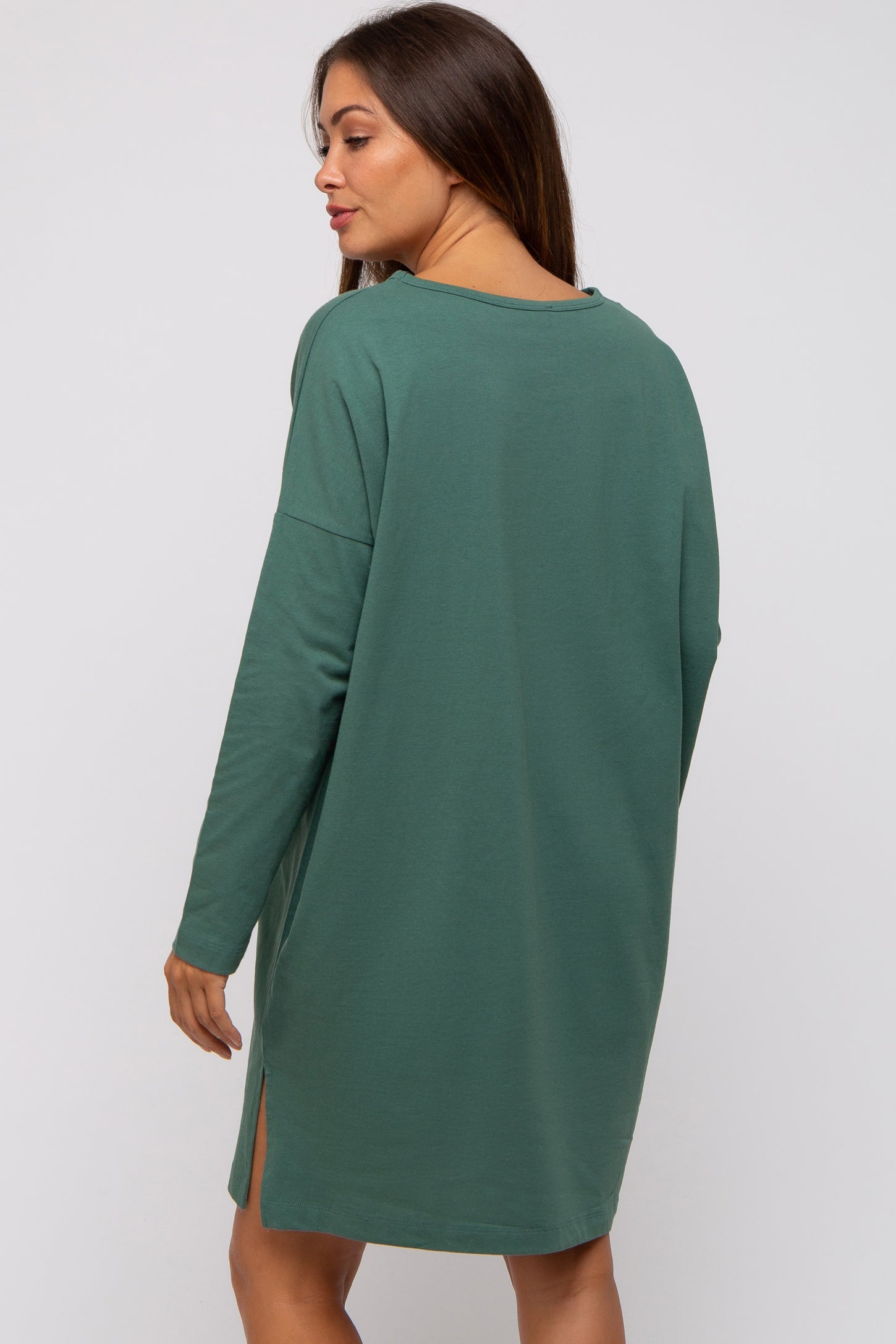 woman wearing a green long sleeve maternity dress with side slits, showing a relaxed fit and comfortable style