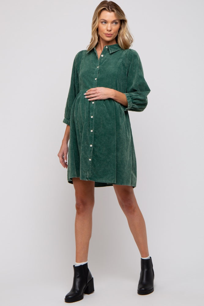woman wearing a green corduroy maternity dress with a button front and a baby bump visible