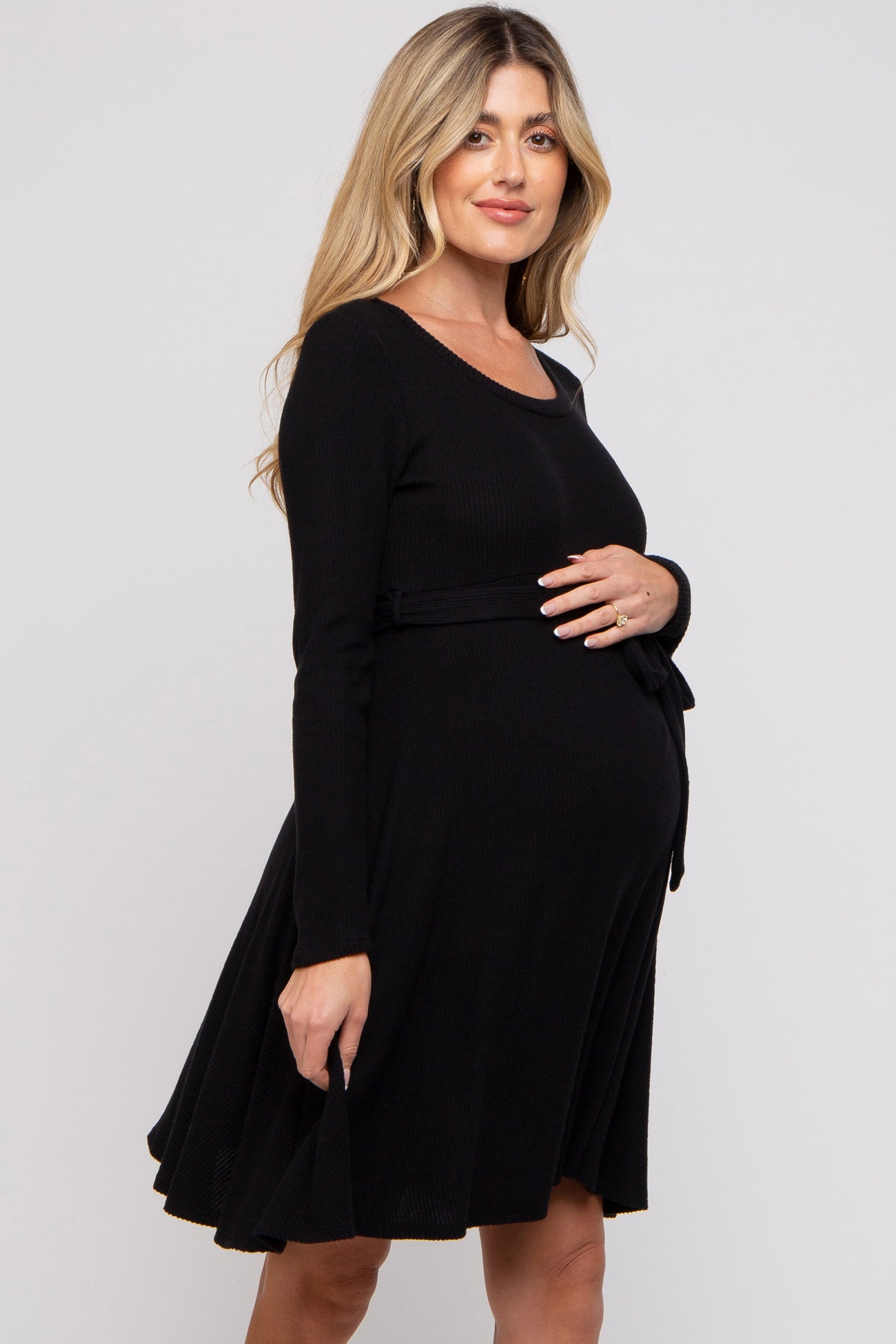 woman wearing a black long sleeve maternity dress with a tie belt, showcasing her baby bump