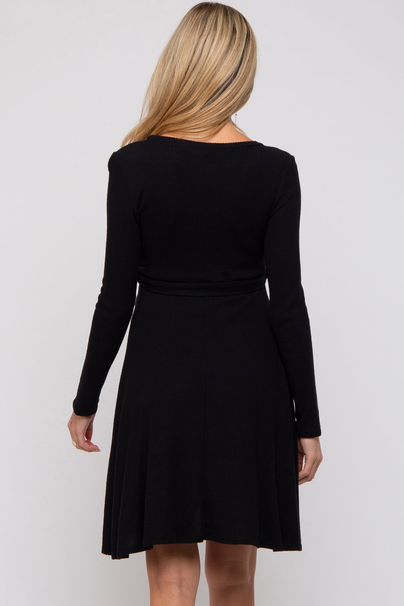 woman wearing a black long sleeve maternity dress with a flared skirt, showing the back view