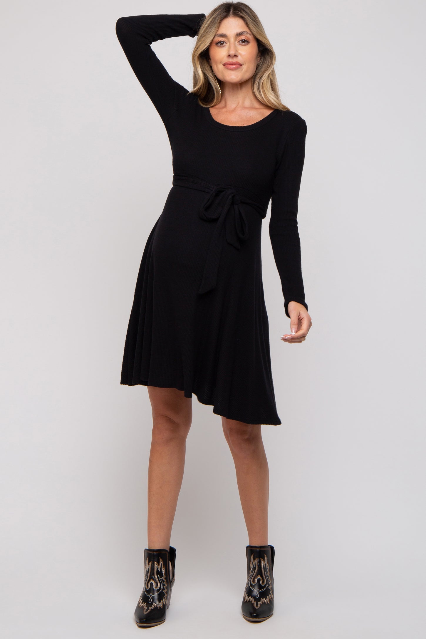 woman wearing a black long sleeve maternity dress with a tie waist and flared skirt, showing her baby bump