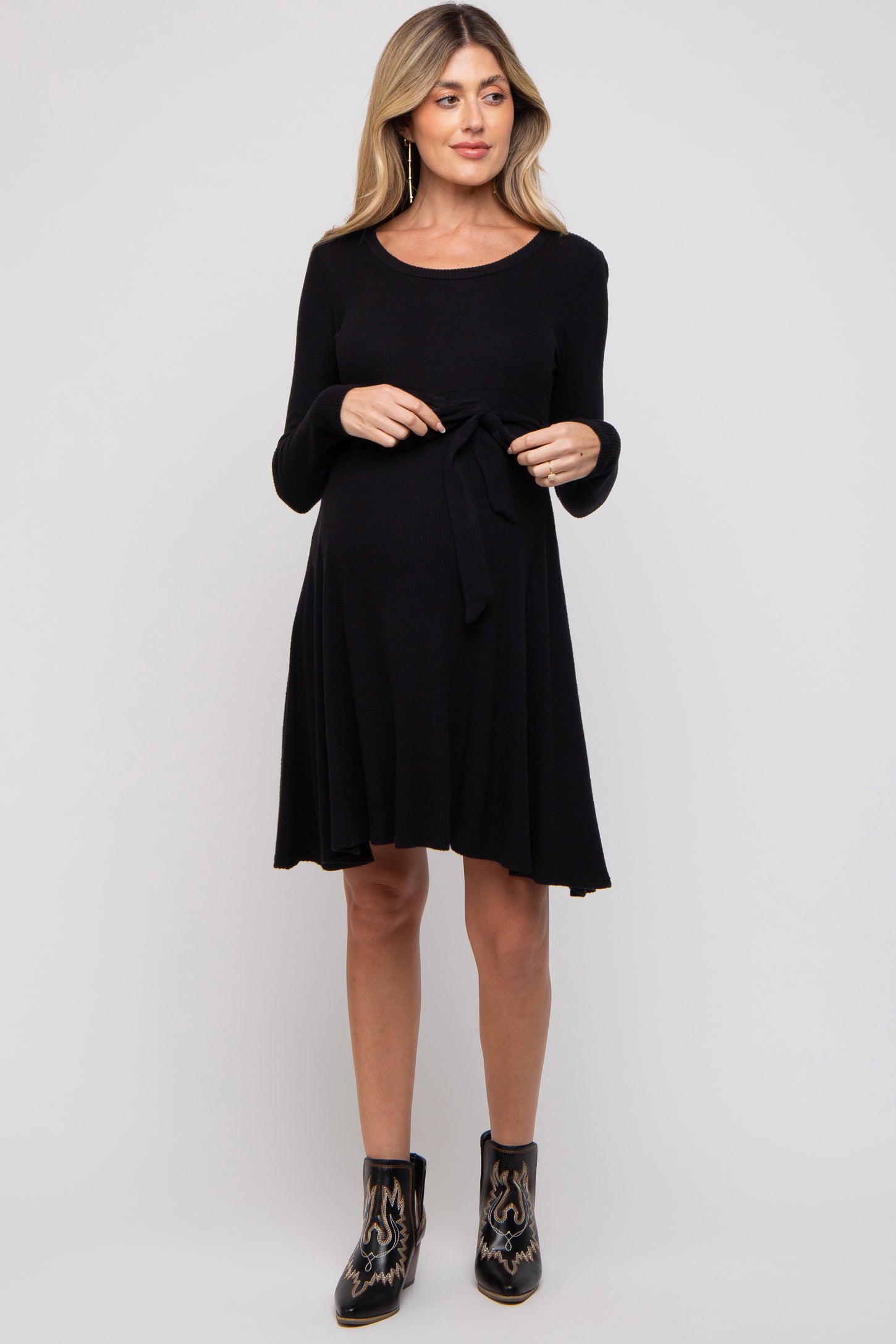 woman wearing a black long sleeve maternity dress with a tie waist and a visible baby bump