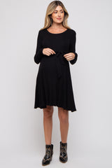 woman wearing a black long sleeve maternity dress with a tie waist and a visible baby bump