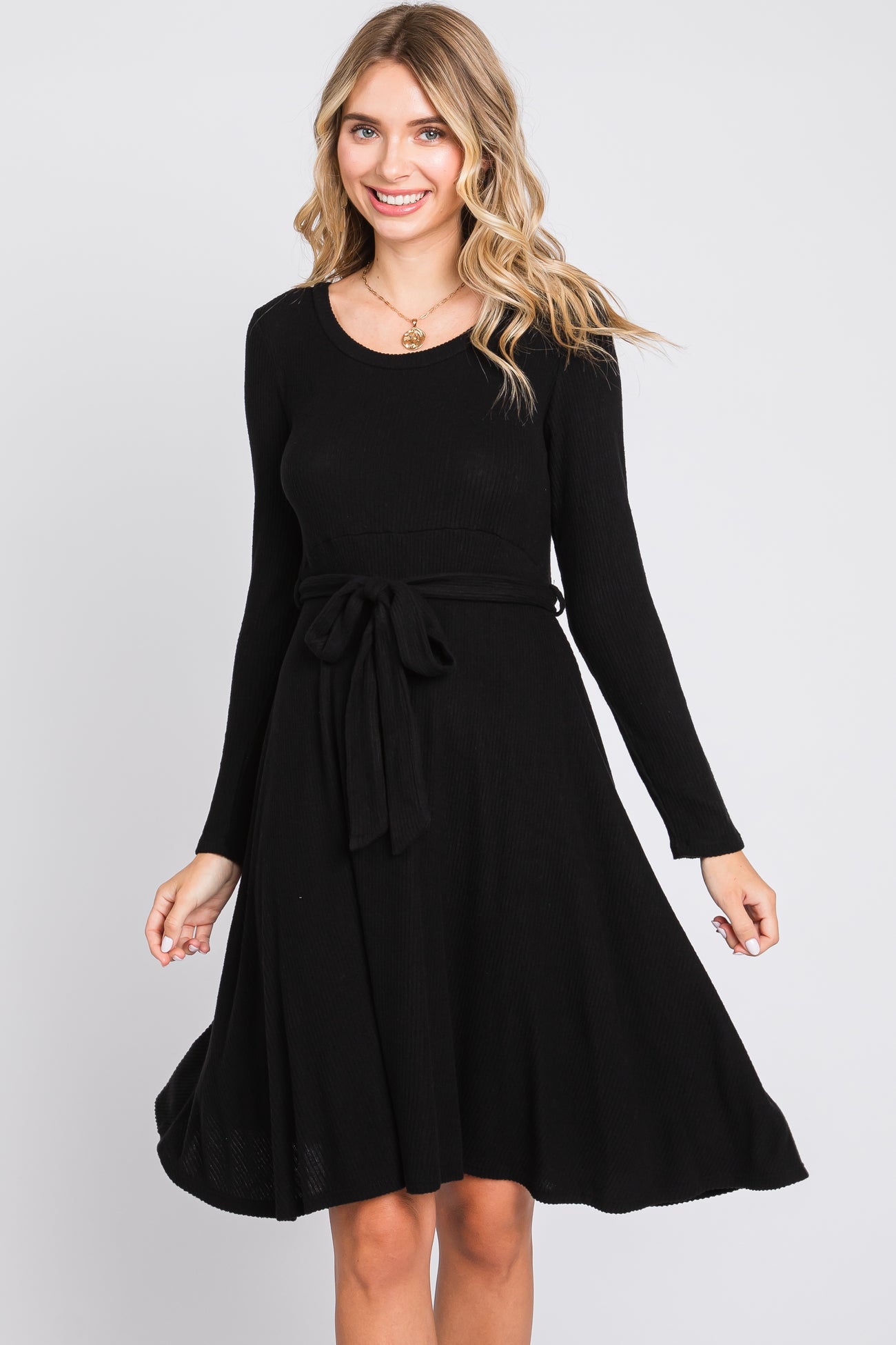 woman wearing a black long sleeve ribbed dress with a tie waist detail and a flared skirt