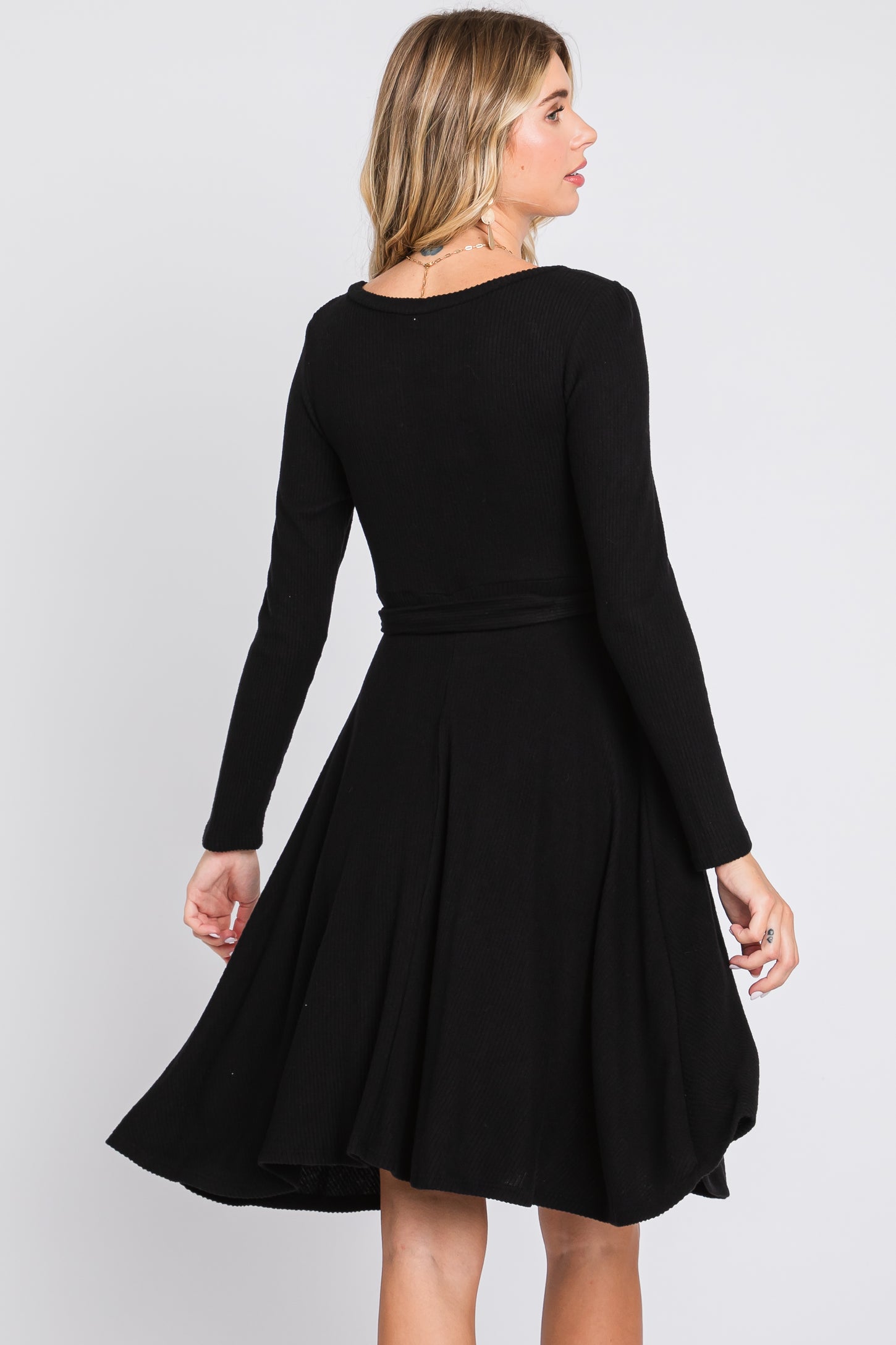 woman wearing a black long sleeve ribbed dress with a flared skirt seen from the back