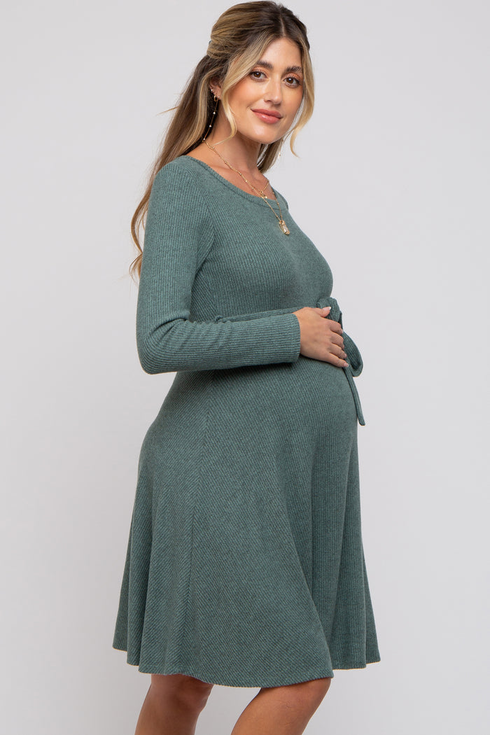 woman wearing a green ribbed maternity dress with long sleeves and a tie waist, highlighting her baby bump