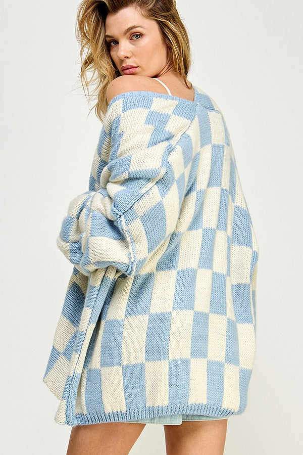 woman wearing an oversized cream and light blue checked knit cardigan, posed with a slight turn to one side