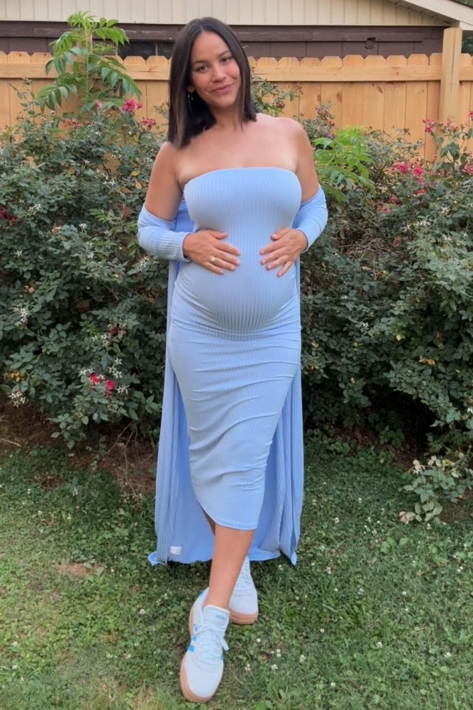 woman wearing a light blue ribbed off-shoulder maternity dress showcasing her baby bump