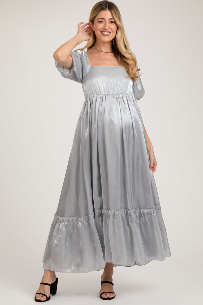 woman wearing a silver satin maternity maxi dress with puff sleeves and ruffled hem