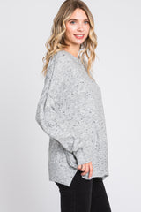 woman wearing a gray oversized sweater with a textured finish and side slits, styled with black skinny jeans
