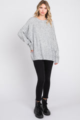 woman wearing a lightweight grey oversized sweater with a loose fit and black skinny jeans, standing with one foot forward